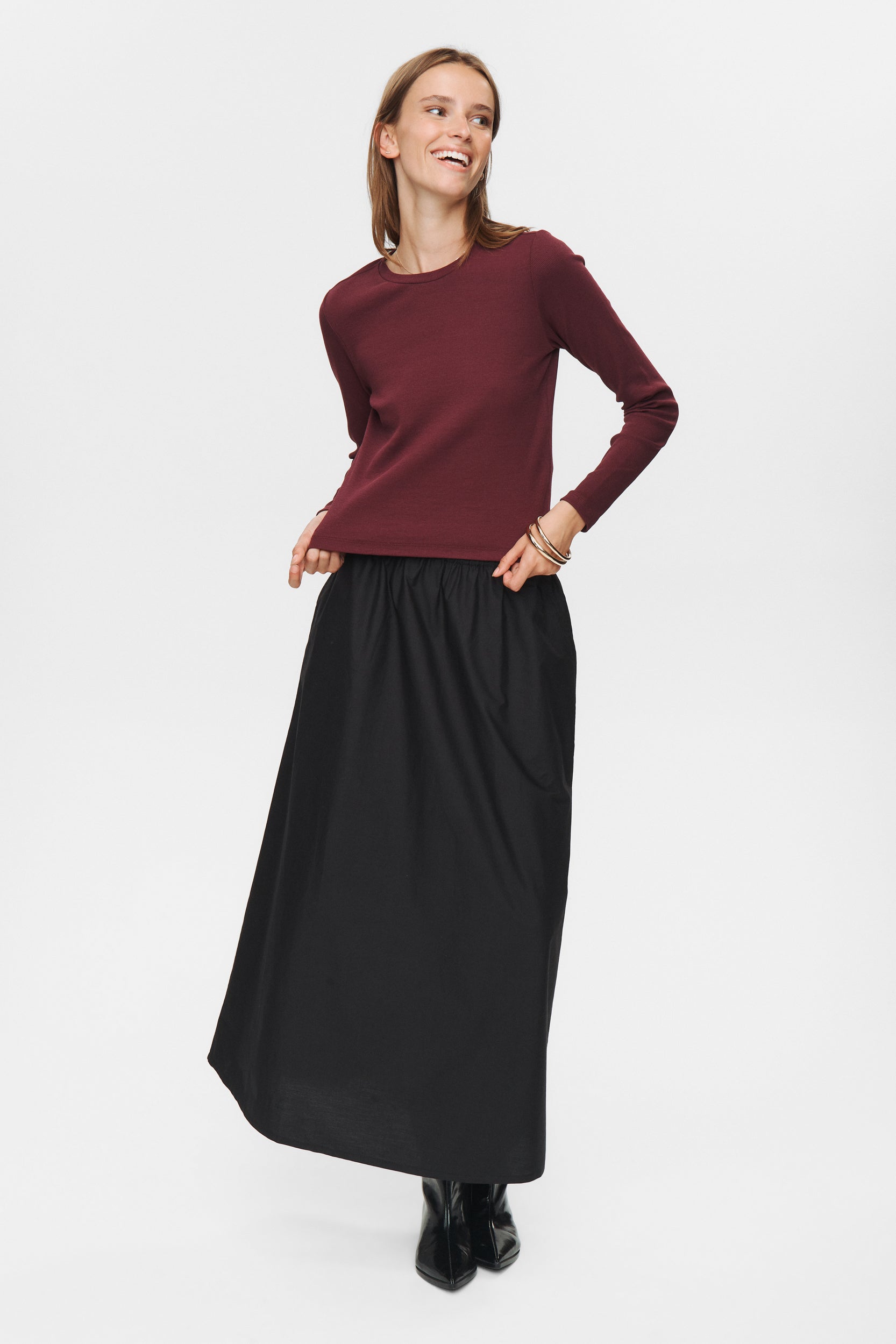 Woman wearing a burgundy sweater and black skirt on a white background