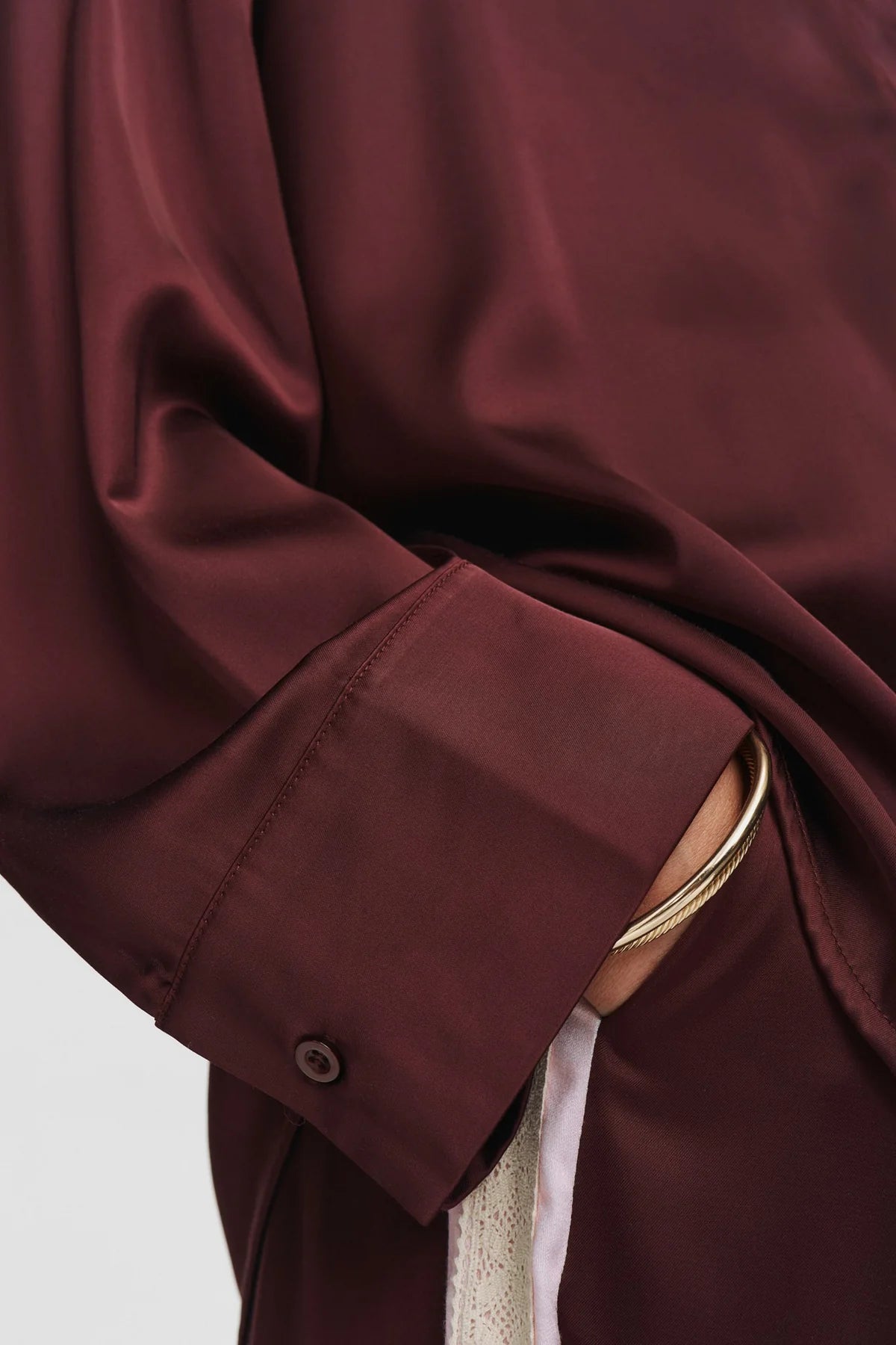 Close-up of a maroon coat with a button on a light gray background