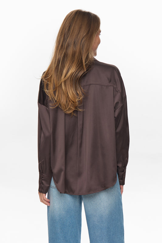 Person wearing a brown jacket and blue jeans on a white background