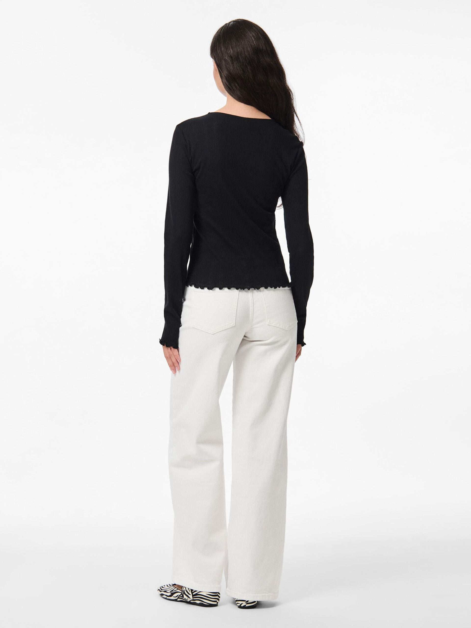 Woman wearing a black top and white pants on a white background