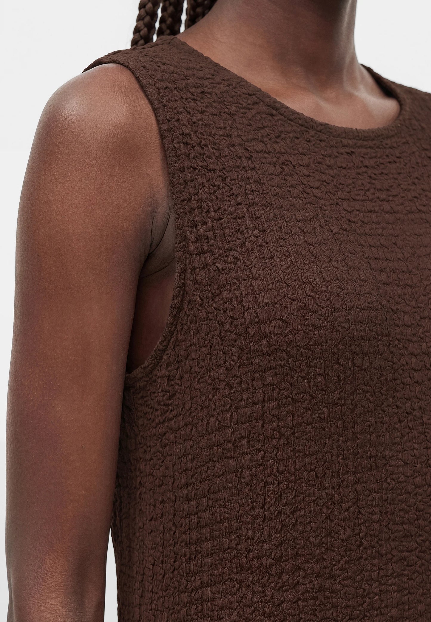 Brown textured sleeveless top worn by a person on a white background