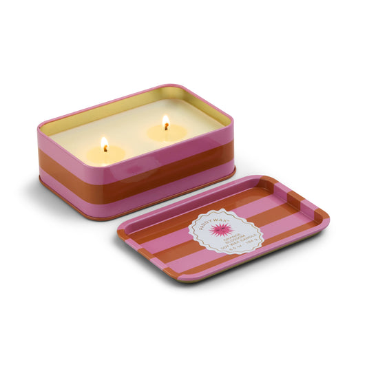 Striped candle tin with two lit candles on a white background