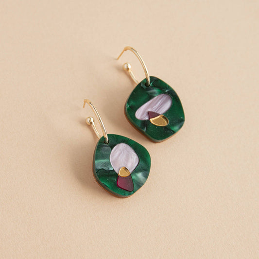 Pair of green earrings with gold accents on a beige background