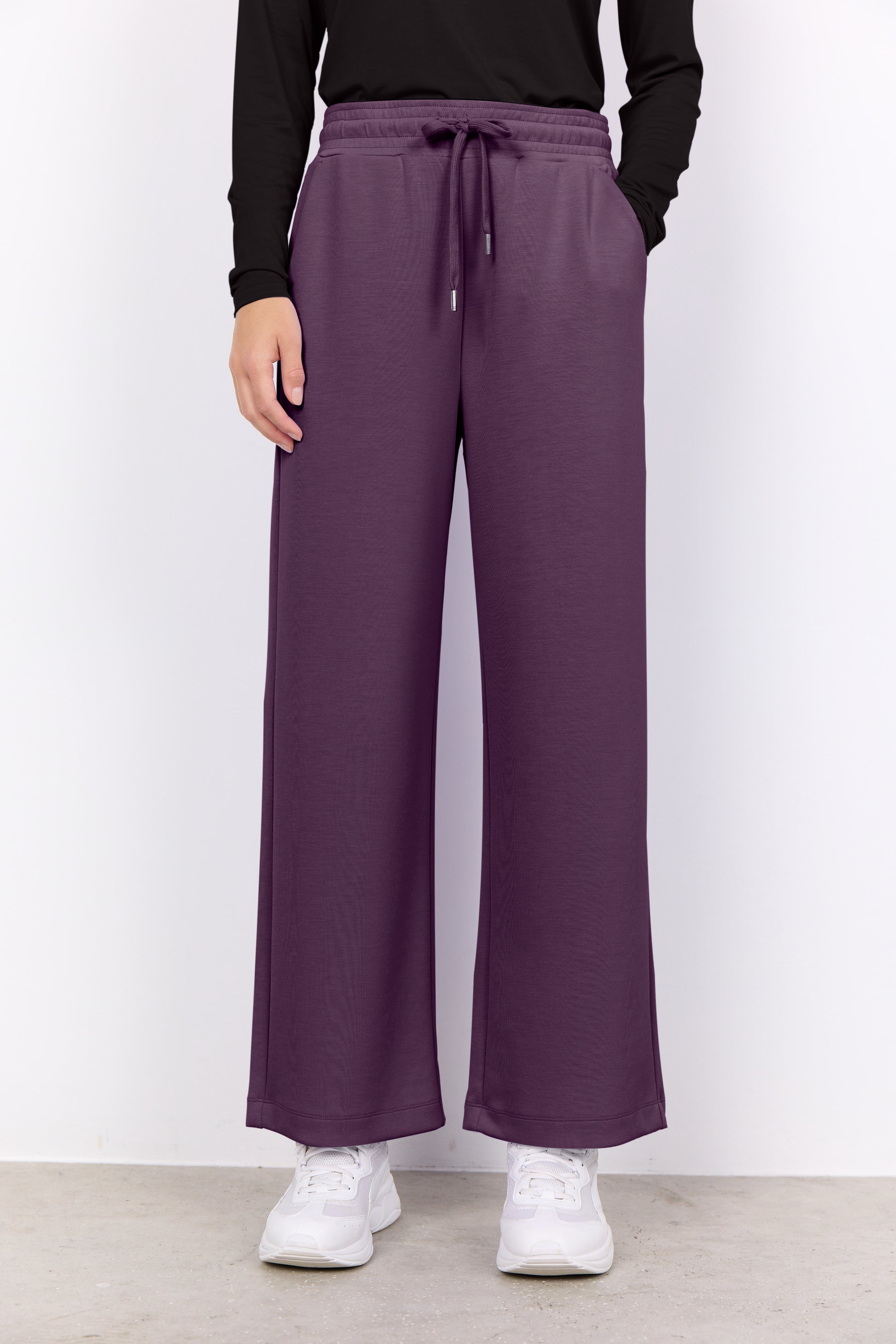 Person wearing purple wide-leg pants with a plain background