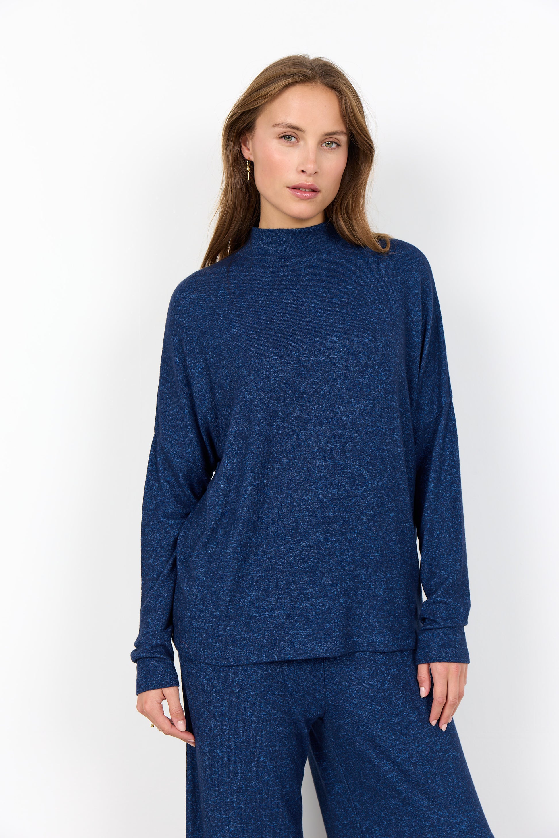 Woman wearing a blue long-sleeve top and pants on a white background