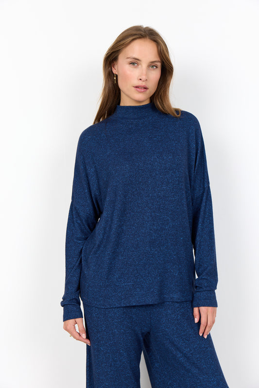 Woman wearing a blue long-sleeve top and pants on a white background