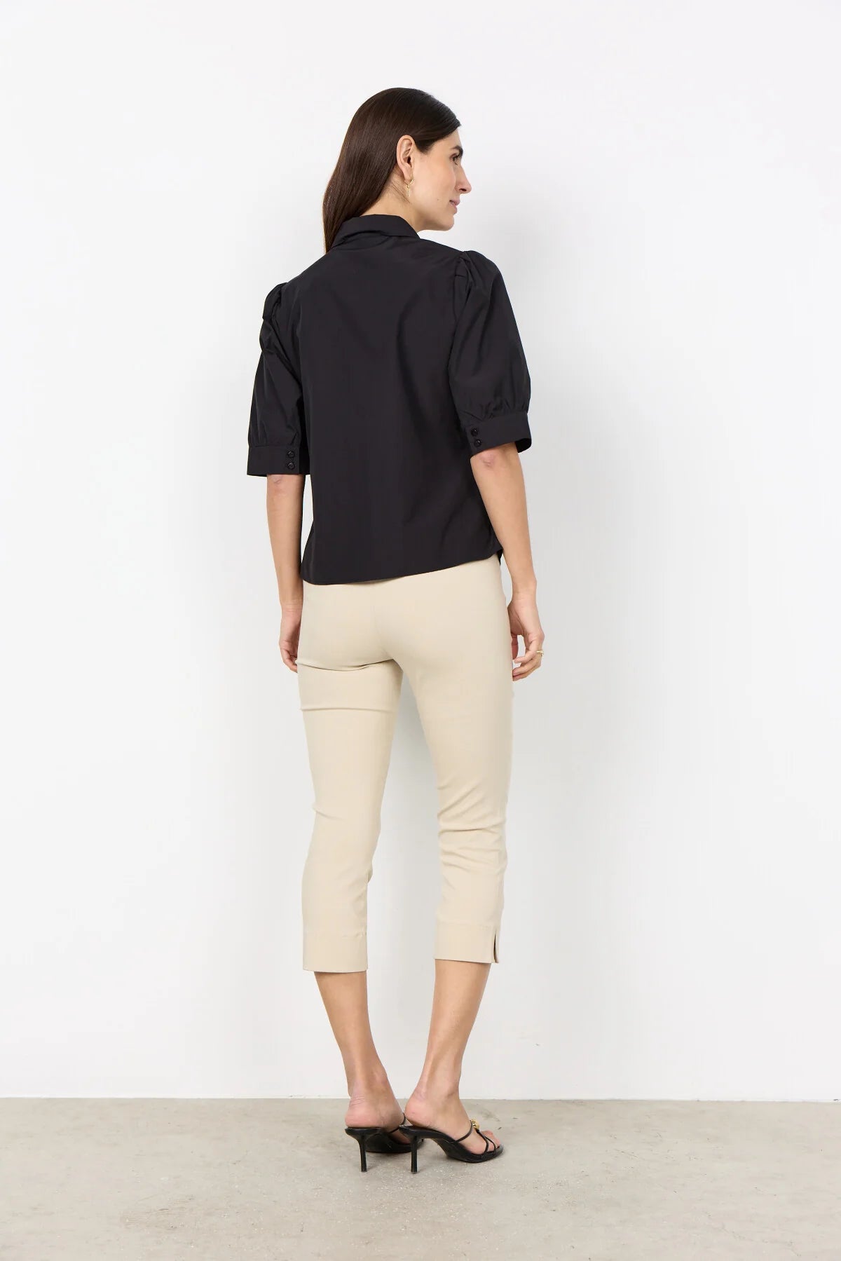 woman wearing a black shirt and cream pants on a white background