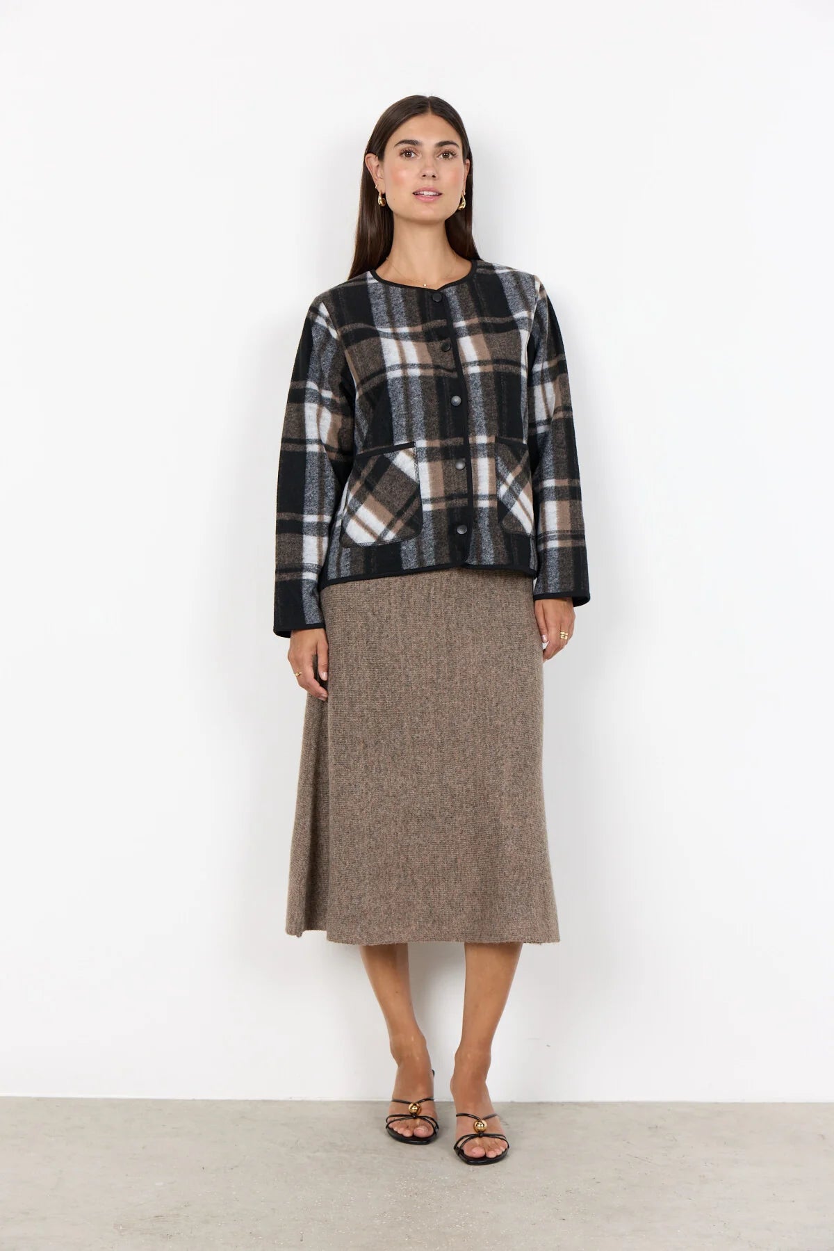 Woman wearing a plaid shirt and brown skirt on a white background