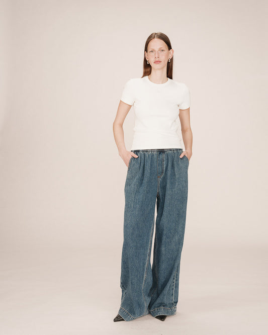 Person wearing a white t-shirt and blue jeans on a plain background