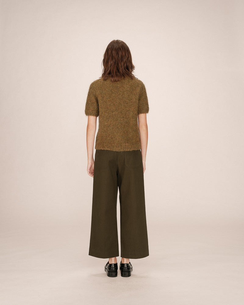 Person wearing a green knitted top and green wide-leg pants on a beige background