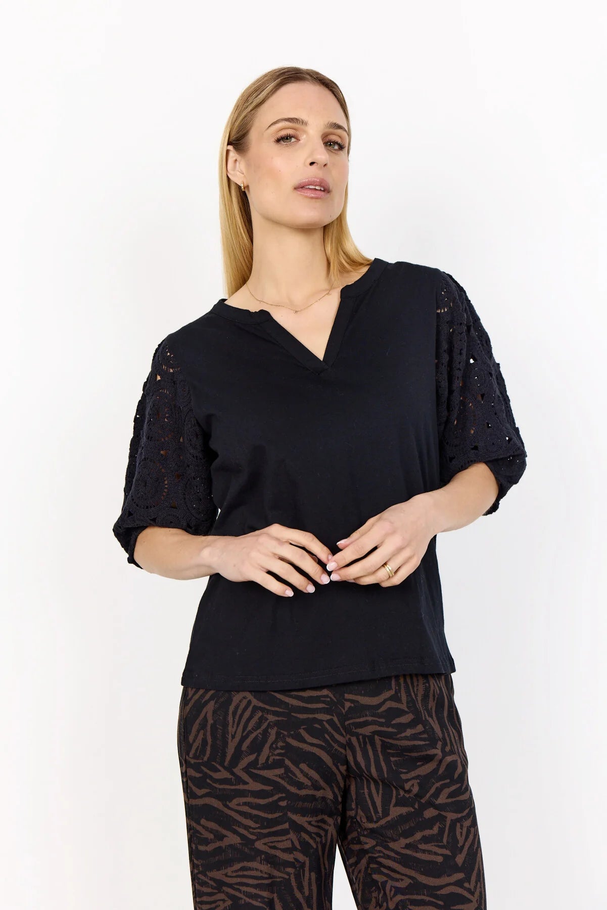 Woman wearing a black top with sequin embellishments on a white background