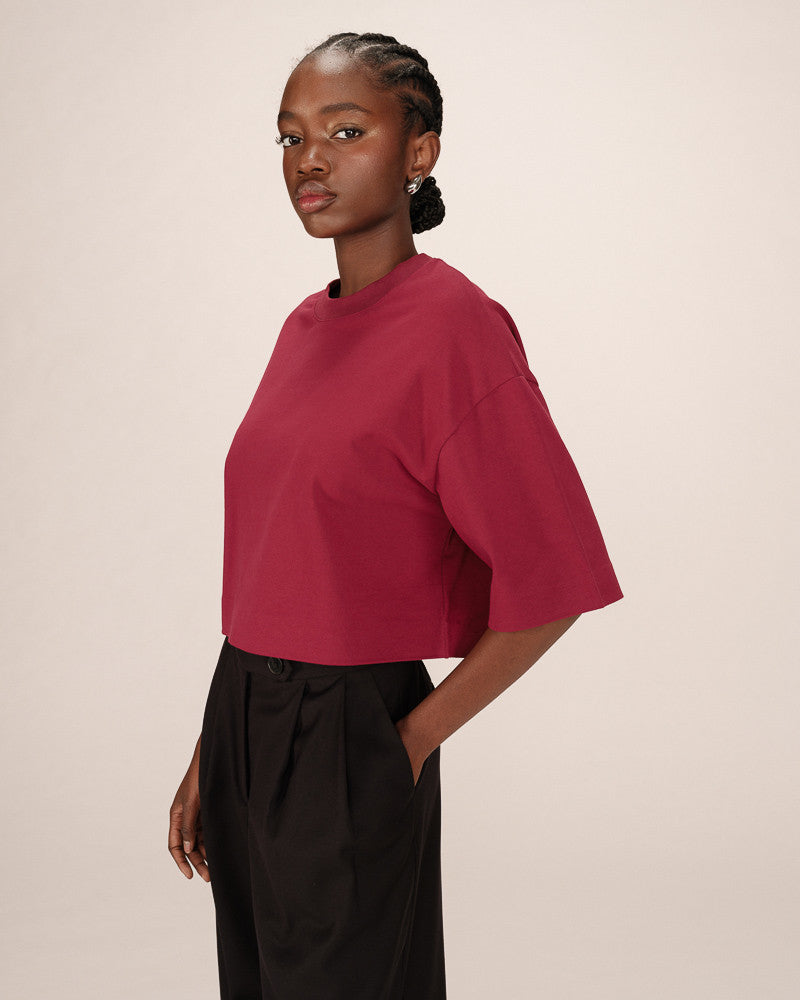 Woman wearing a red top and black pants against a beige background