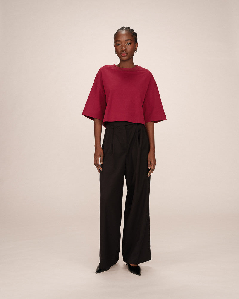 Person wearing a red top and black pants on a plain background