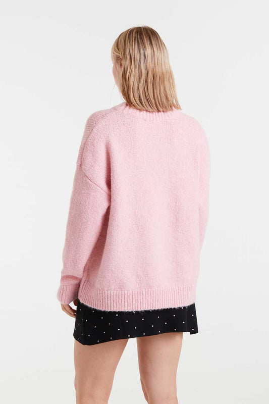 Person wearing a pink sweater and black polka dot skirt on a white background