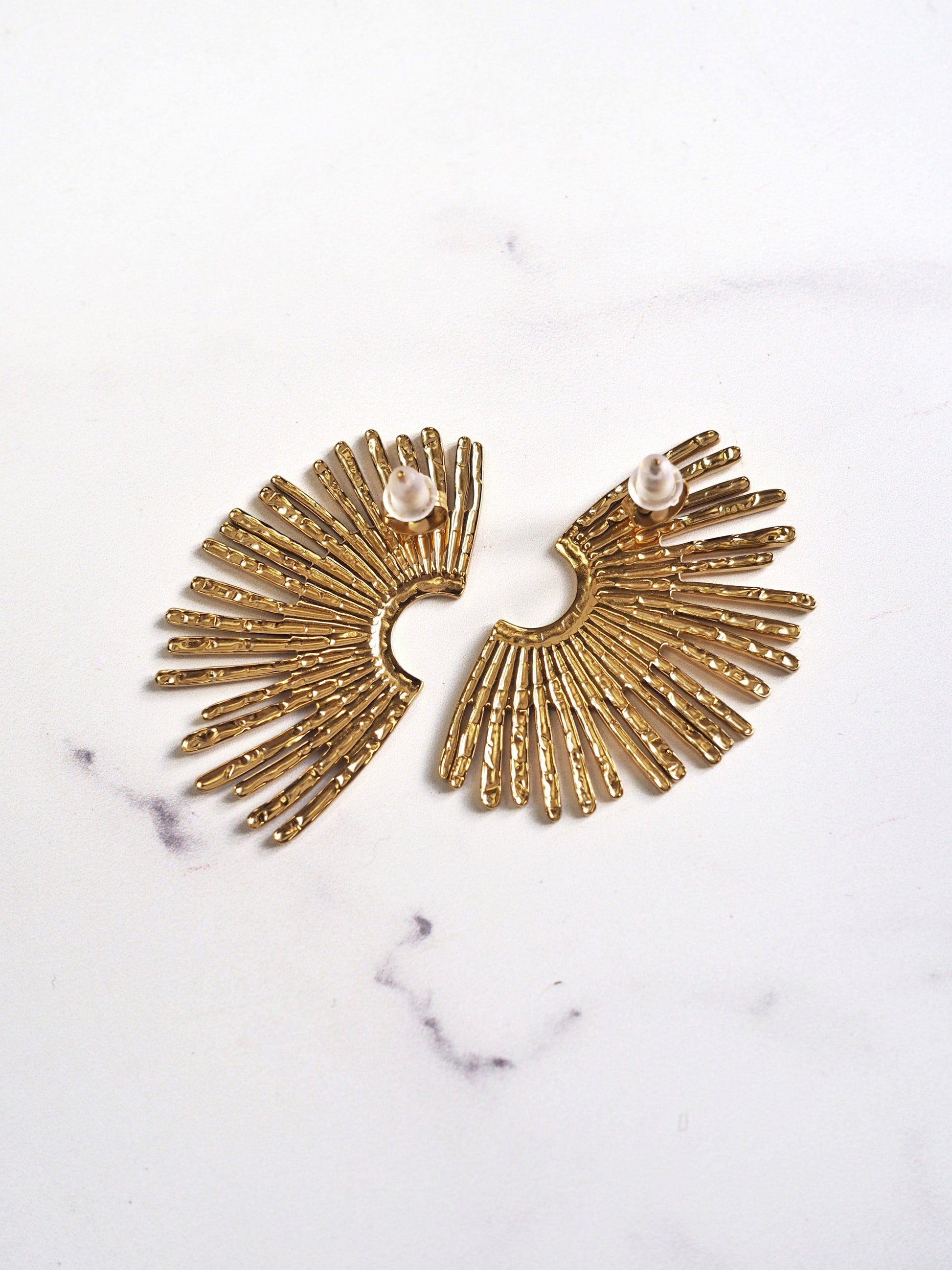 Gold earrings with pearl accents on a marble surface