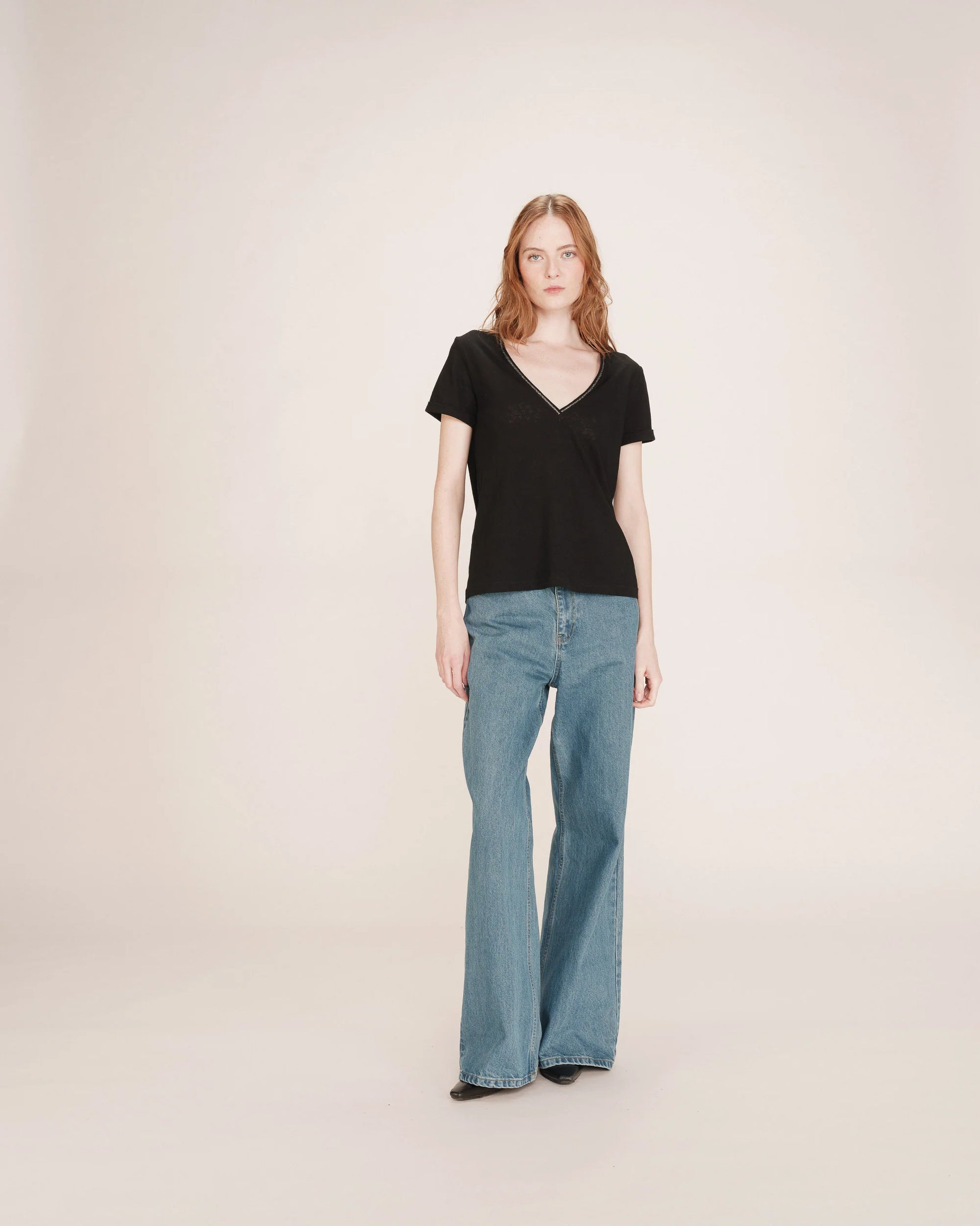 Woman wearing a black top and blue jeans on a plain background