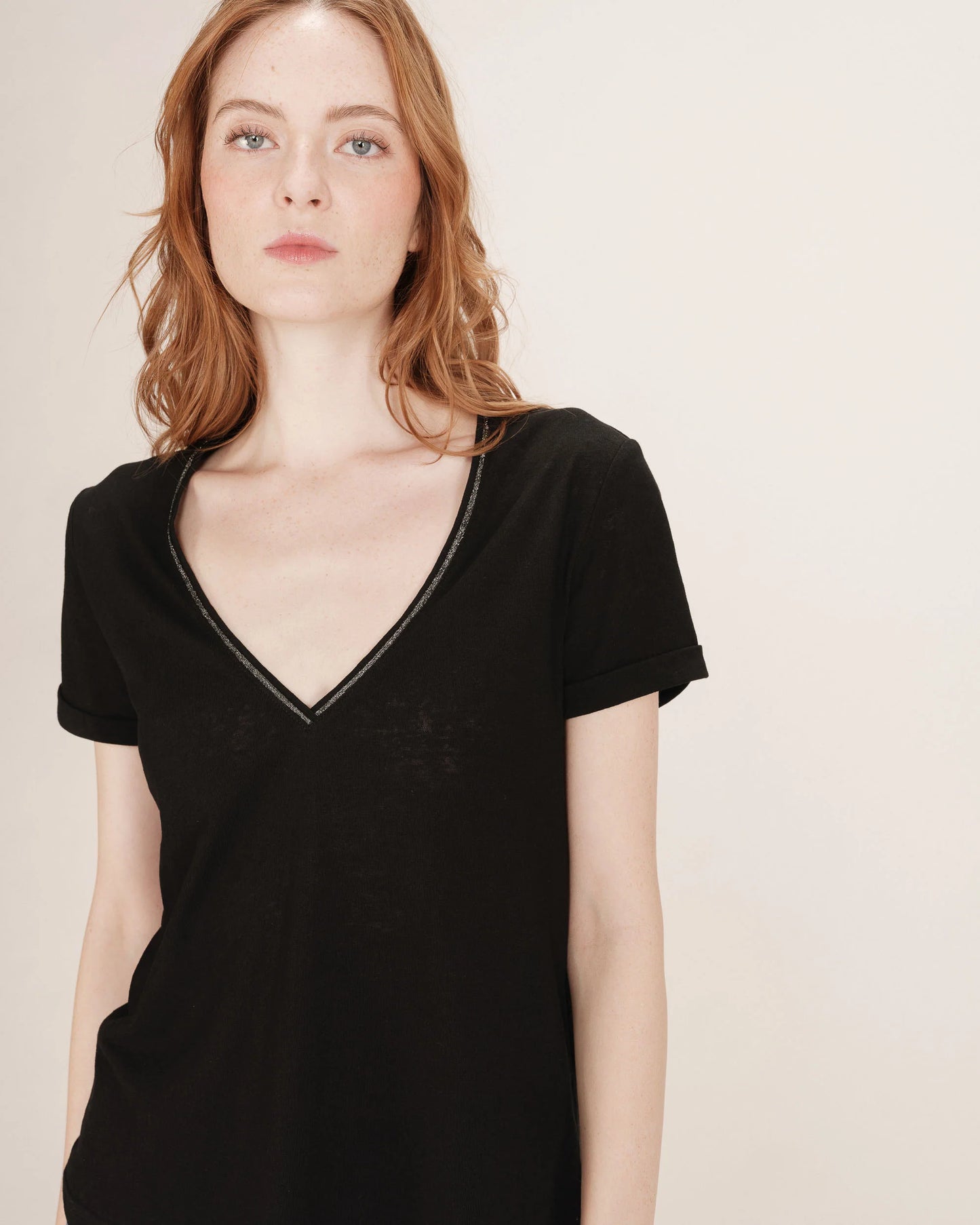 Woman wearing a black V-neck top against a plain background