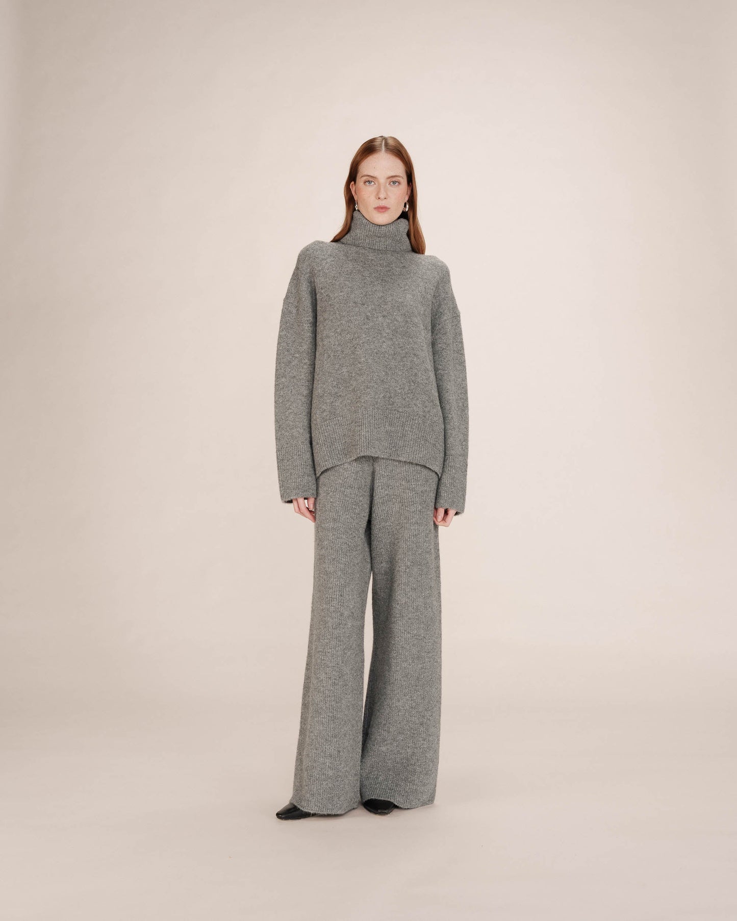 Woman wearing a gray knit outfit on a plain background