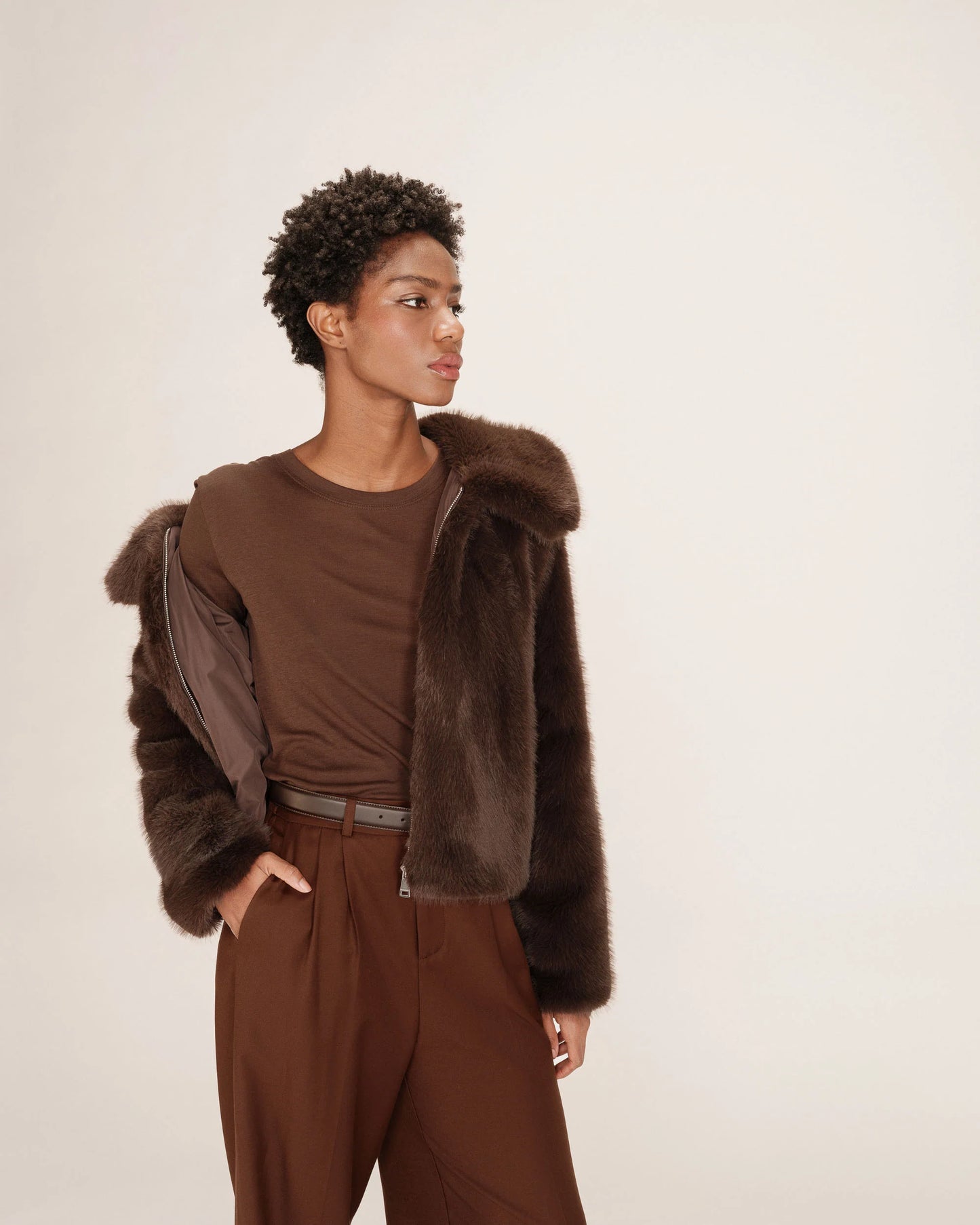 Person wearing a brown fur jacket and pants on a plain background