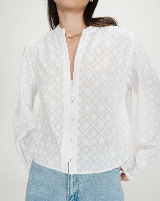 White quilted blouse worn by a person on a plain background
