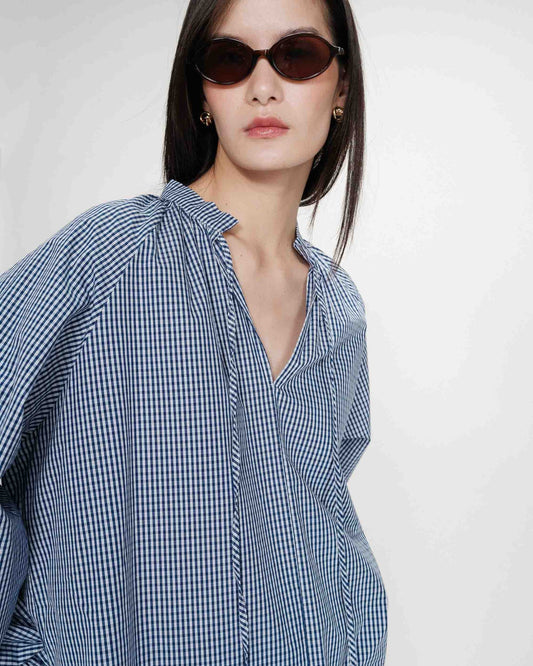 Woman wearing a blue checkered shirt and sunglasses on a white background