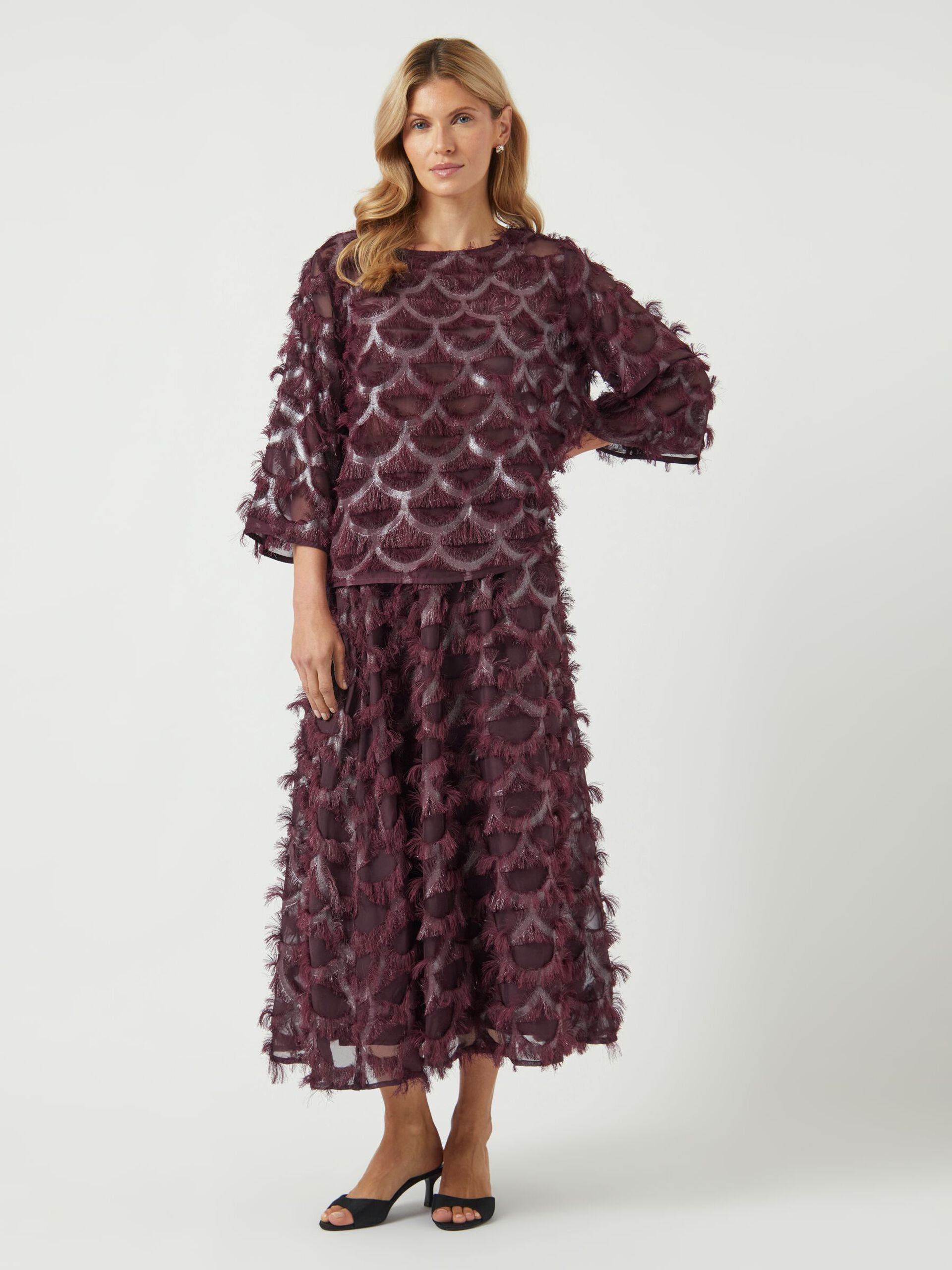 Woman wearing a dark purple lace top and skirt on a white background