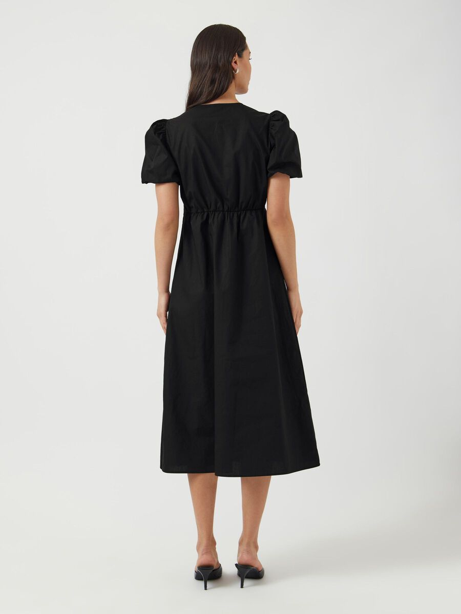 Woman wearing a black dress with puff sleeves on a white background