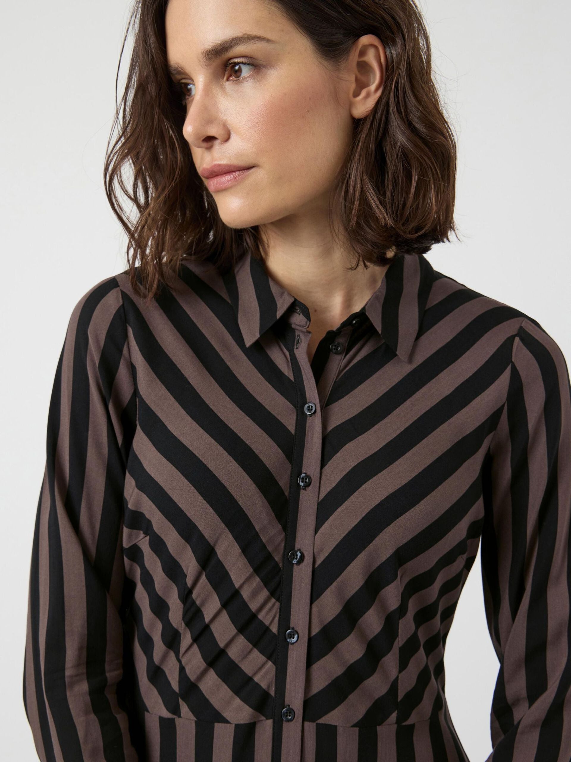 Woman wearing a black and brown striped dress on a white background
