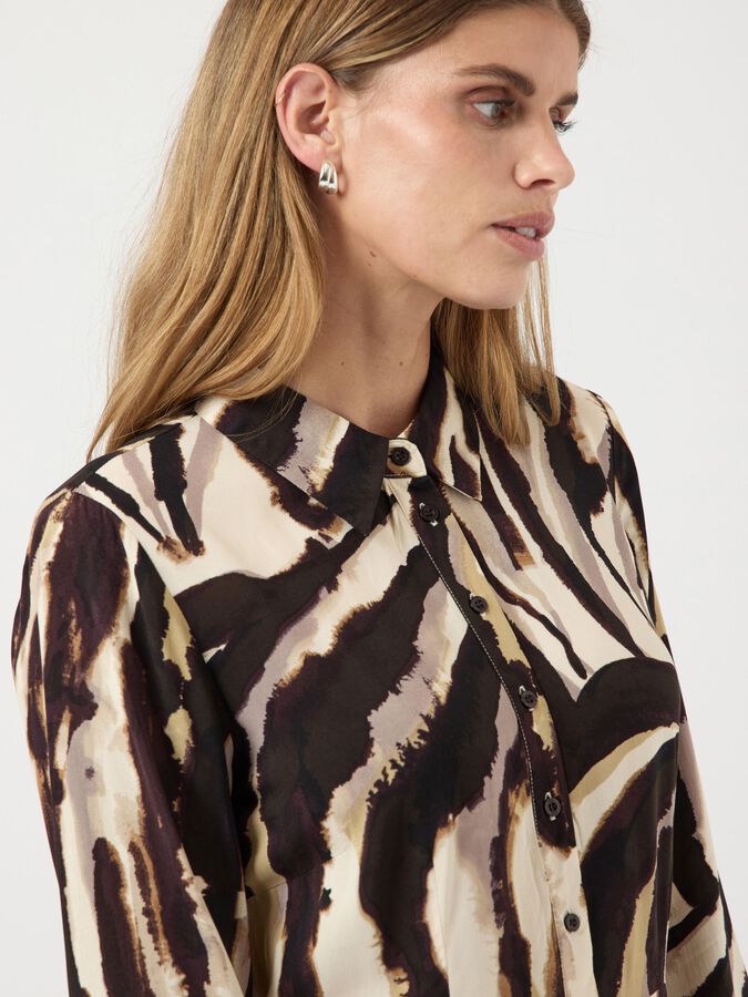 Woman wearing a patterned shirt with a neutral background