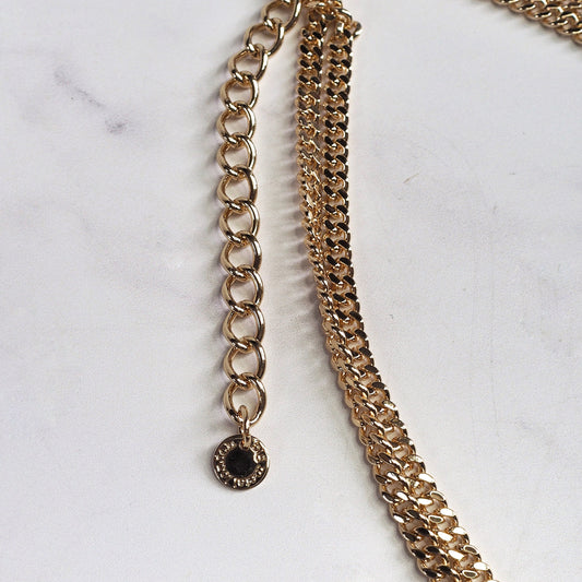 Gold chain belt with a black accent on a white marble background