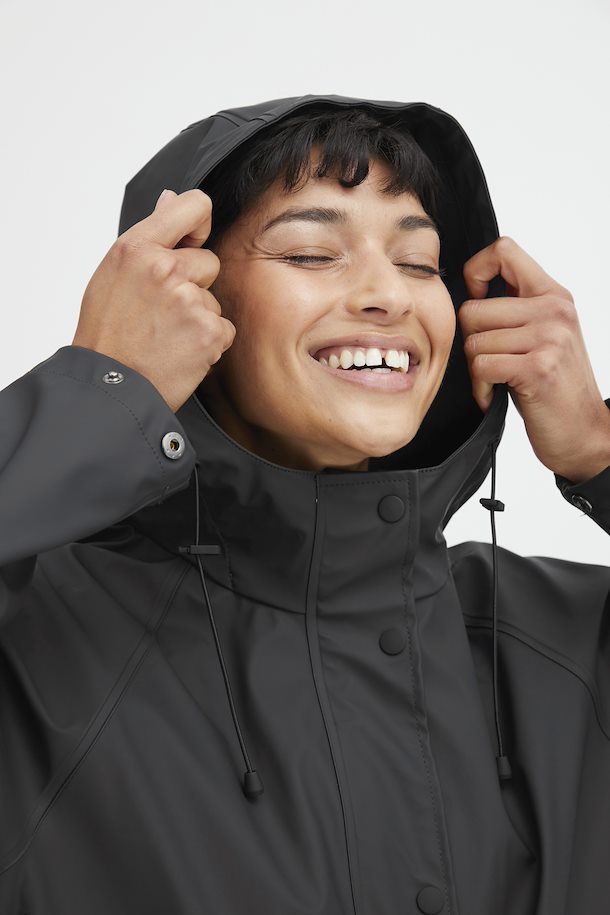 person in a black raincoat with a white background