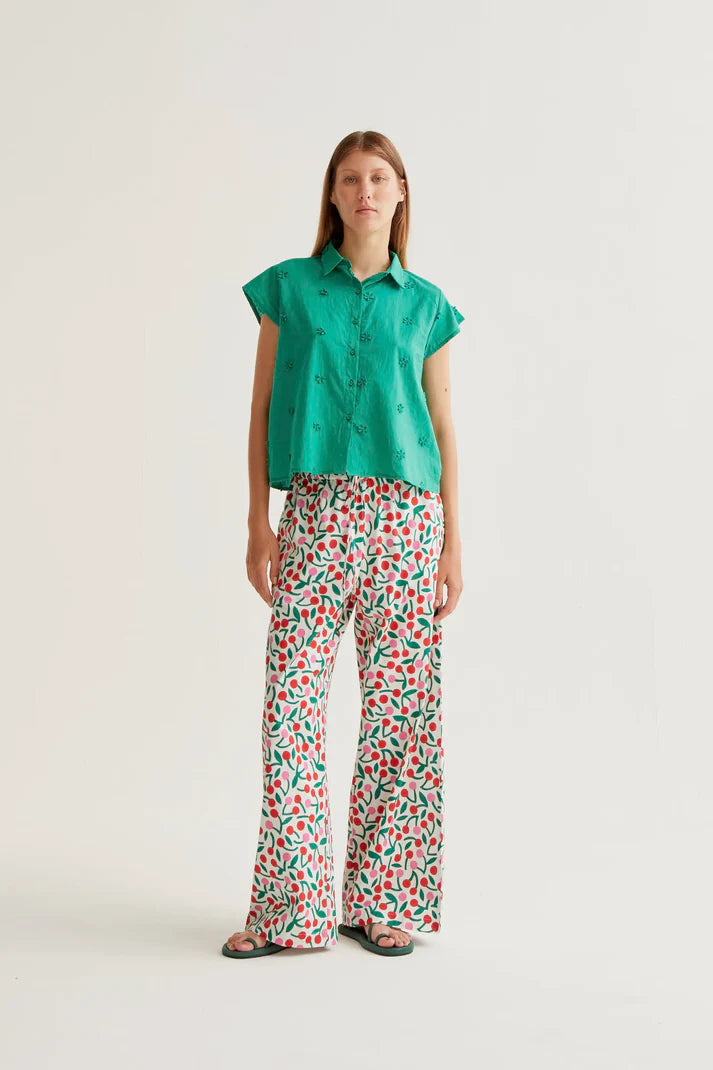 Woman wearing a green shirt and patterned pants on a white background