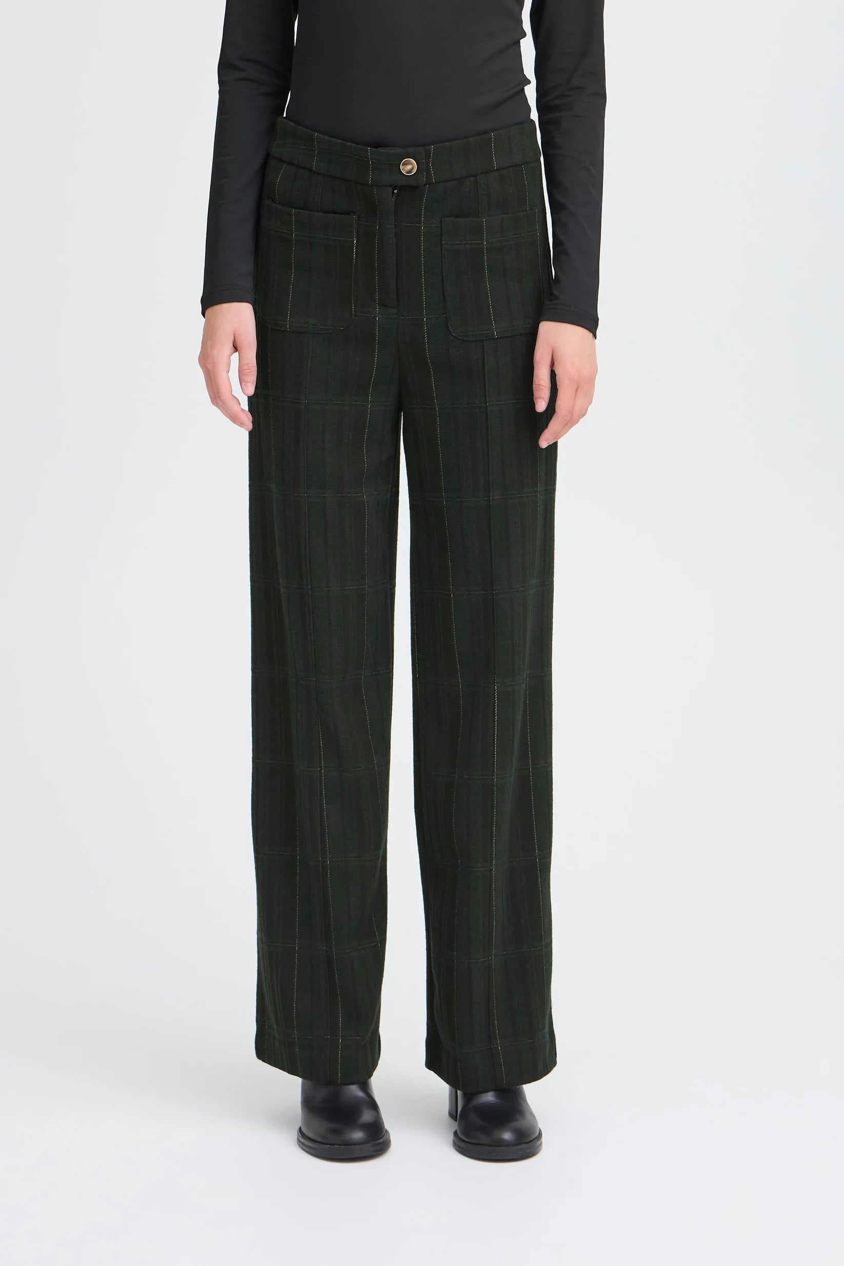 Person wearing dark green plaid pants on a white background