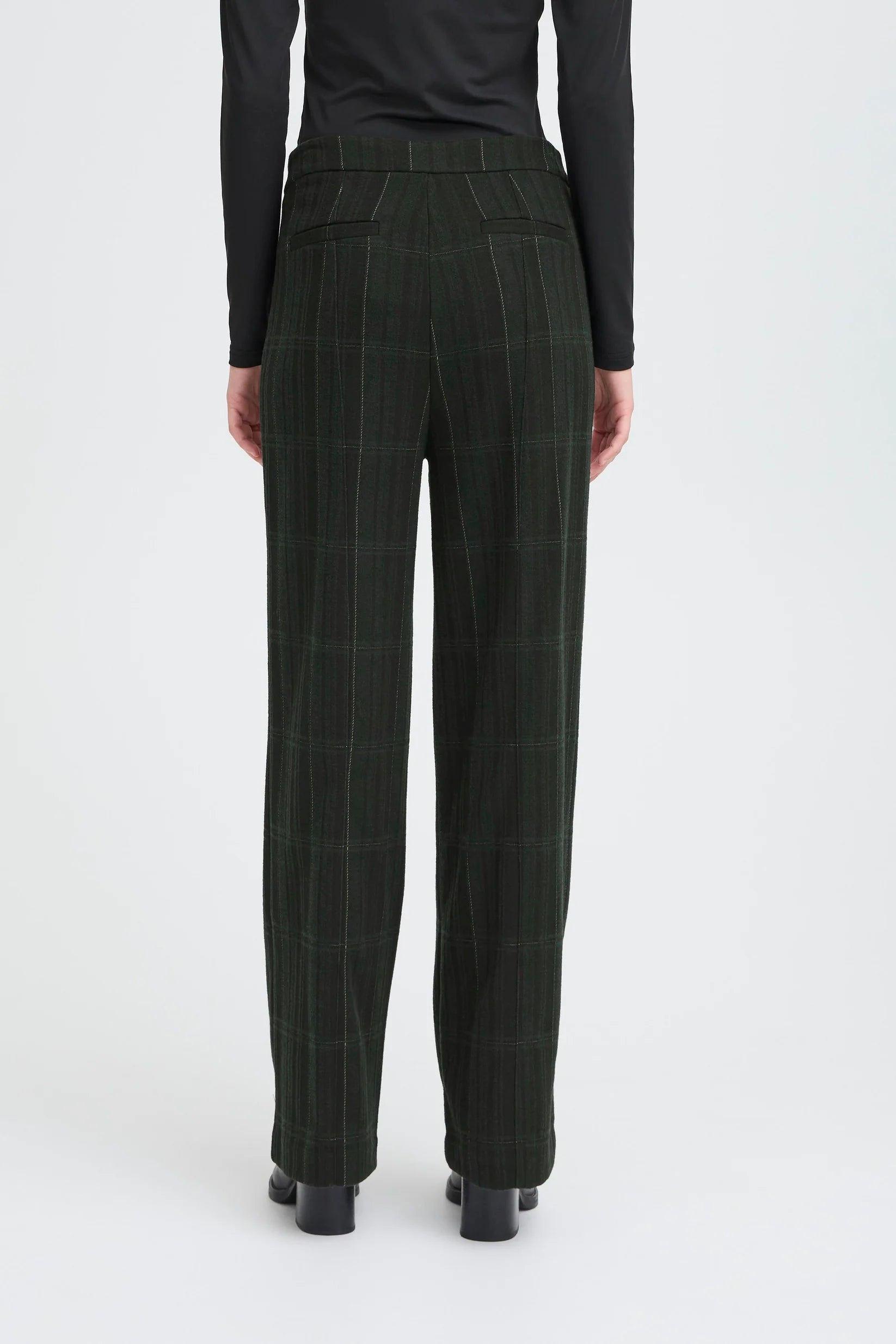 Person wearing dark green checkered pants on a white background