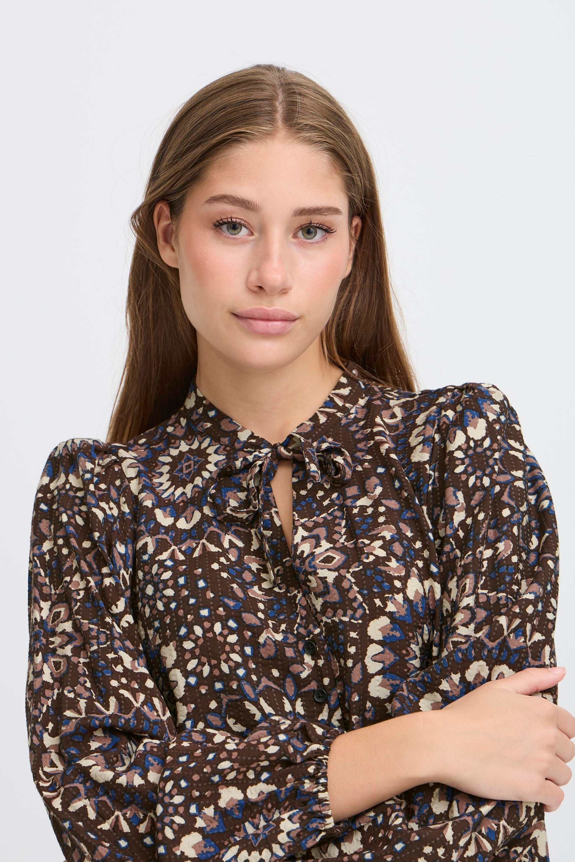 Woman wearing a patterned blouse against a white background