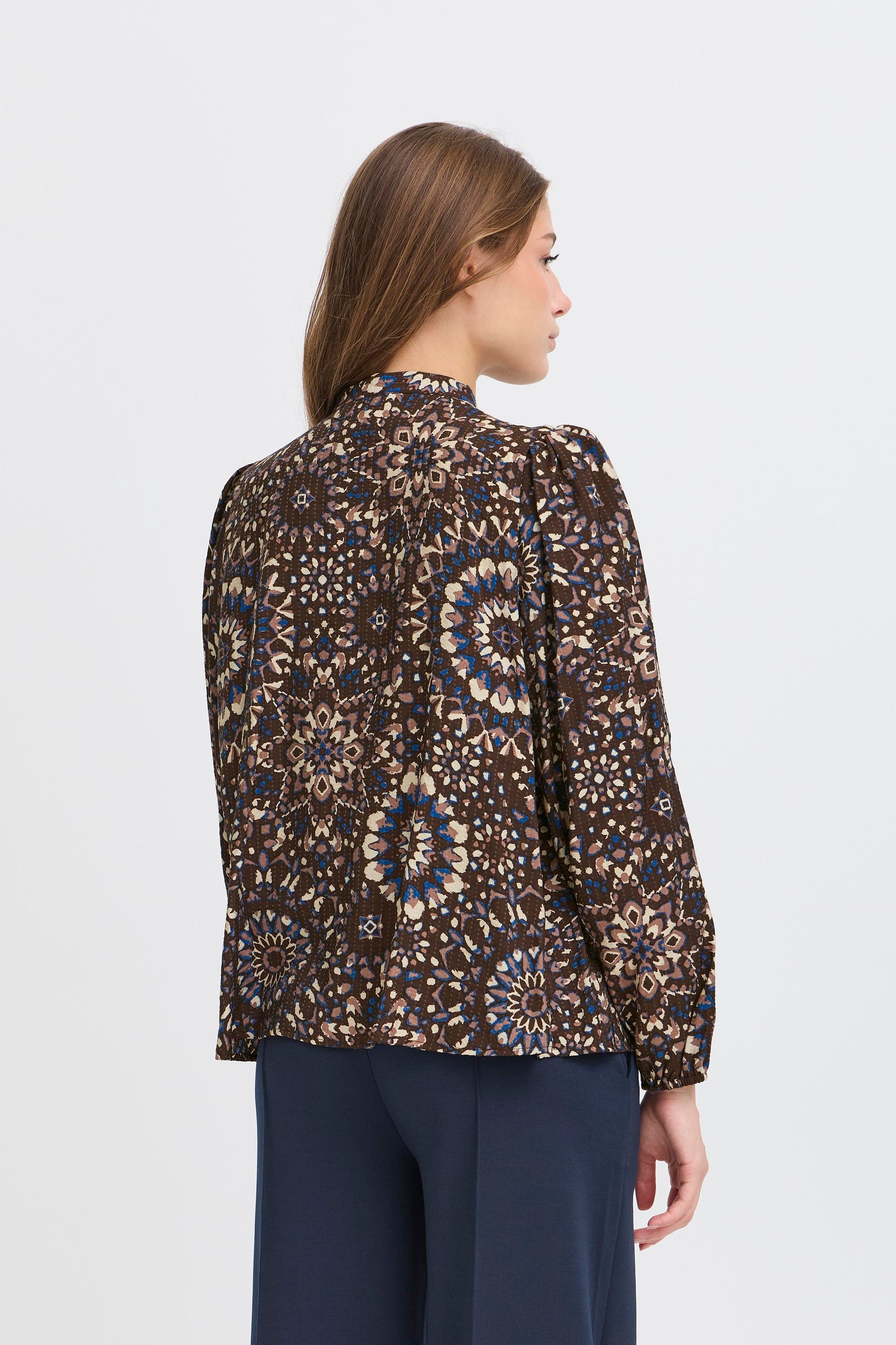 Woman wearing a patterned blouse with a plain background