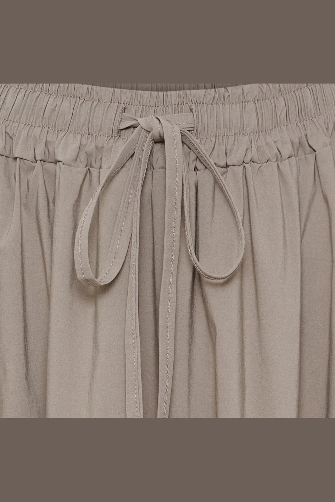 Close-up of a light taupe drawstring waist skirt with a gathered elastic waistband.
