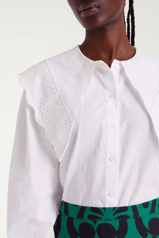 White blouse with intricate collar design worn by a person against a white background