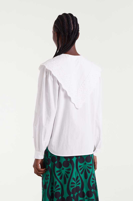 Person wearing a white blouse and green patterned skirt on a white background