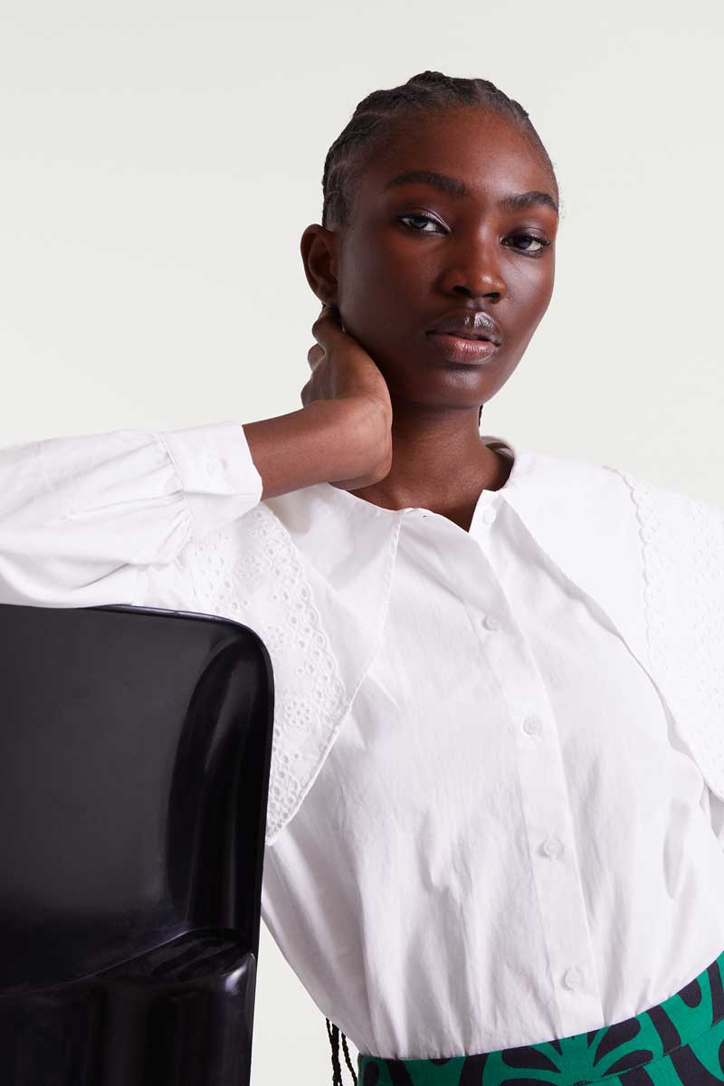 Woman wearing a white blouse with a black chair and white background