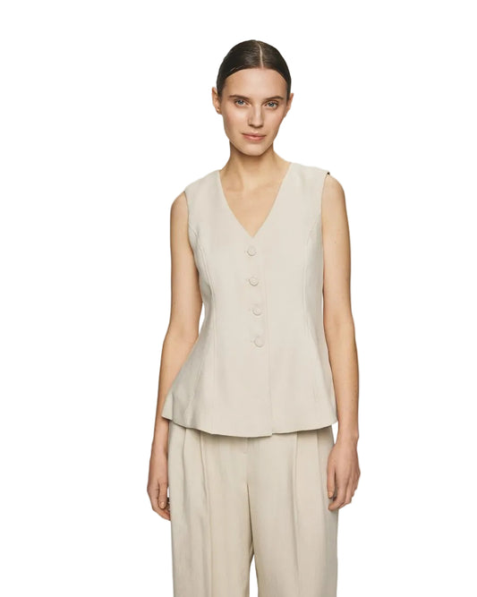 Woman wearing a beige sleeveless top and pants on a light gray background