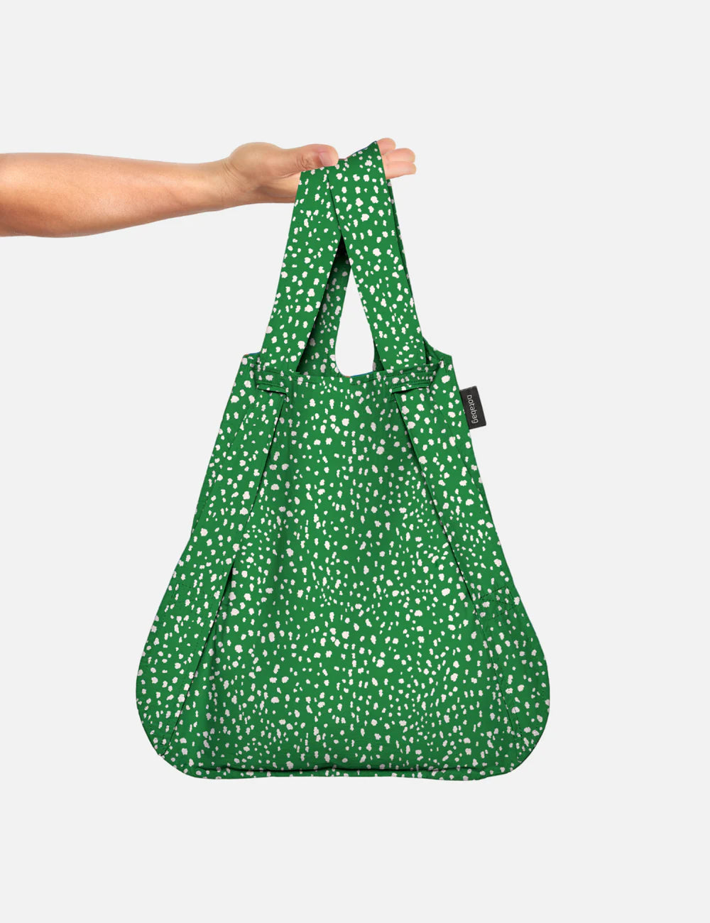 Green patterned reusable bag held by a person on a white background