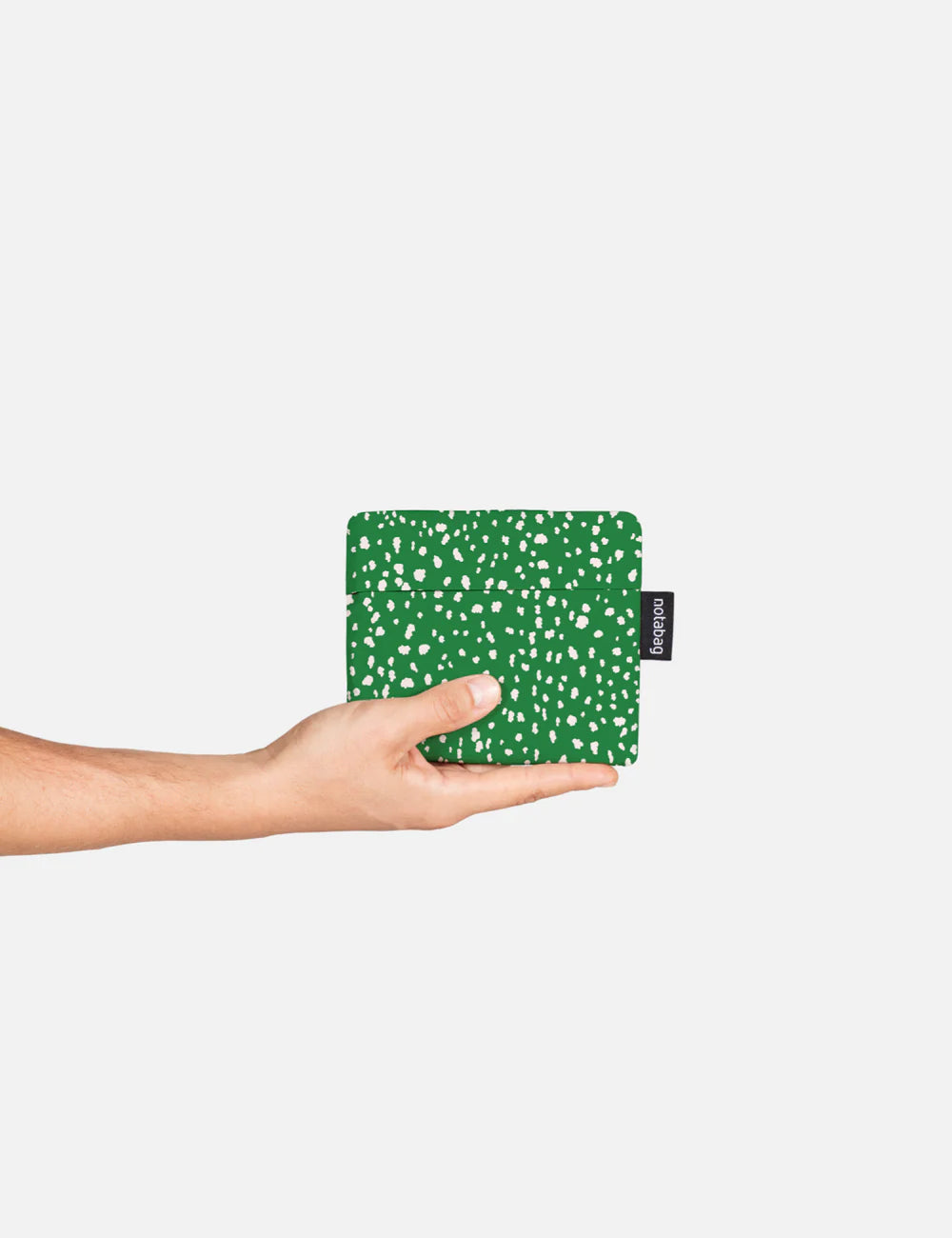 Hand holding a green patterned product against a white background