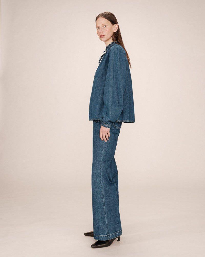 Woman wearing a blue denim outfit on a beige background