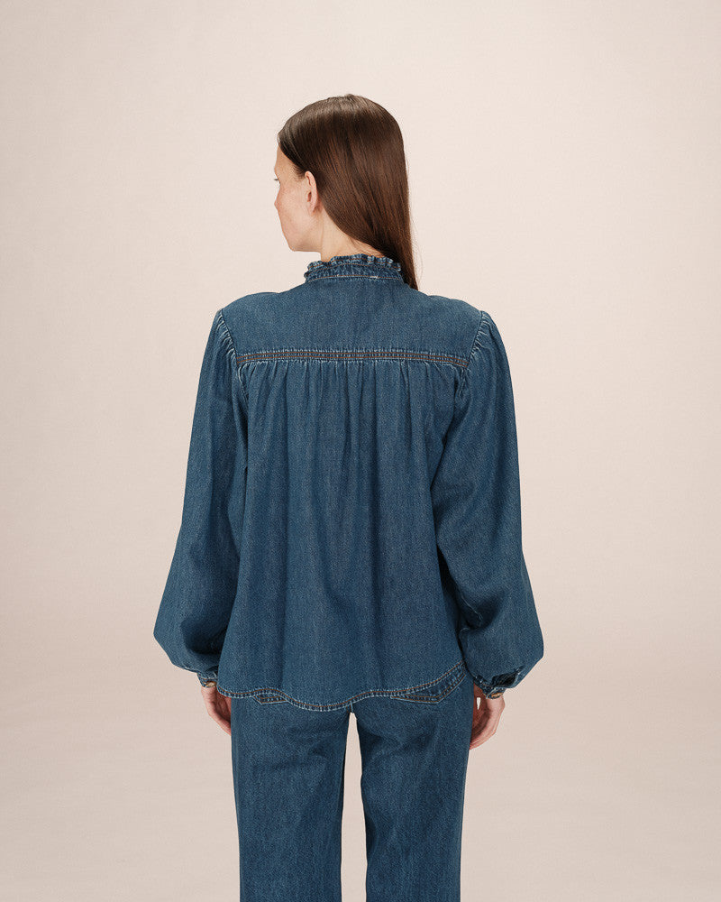Person wearing a blue denim outfit on a beige background