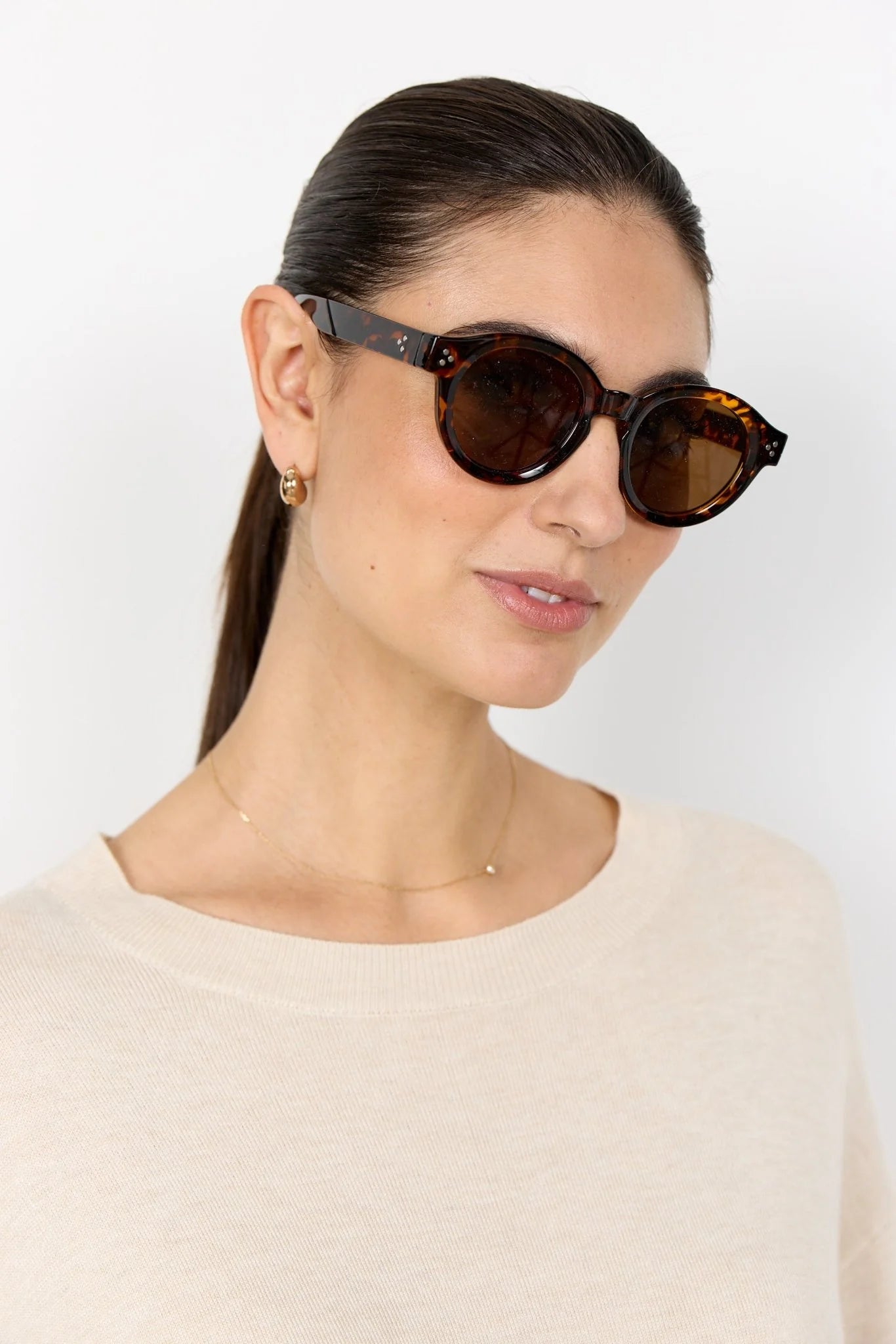 Woman wearing brown sunglasses against a white background