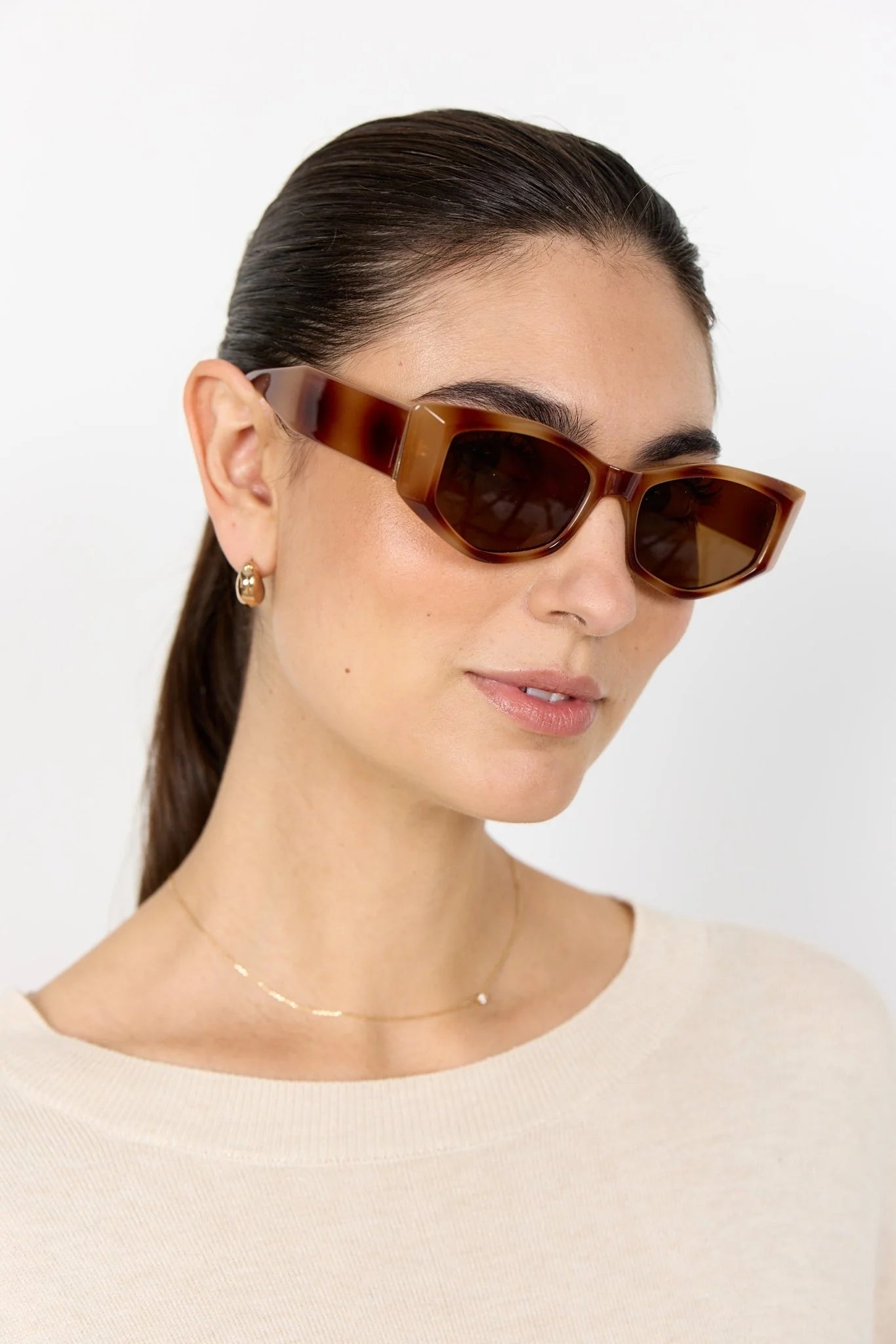 Woman wearing brown sunglasses against a white background