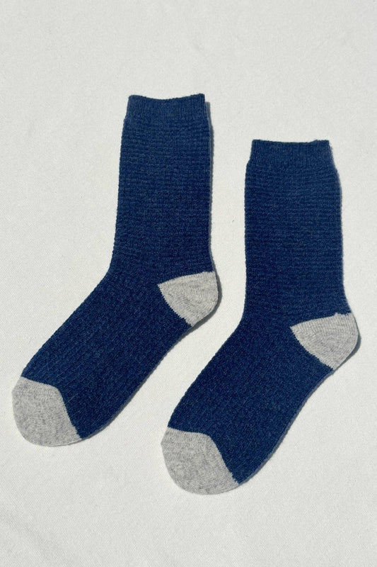 Pair of blue socks with gray toes and heels on a light gray background