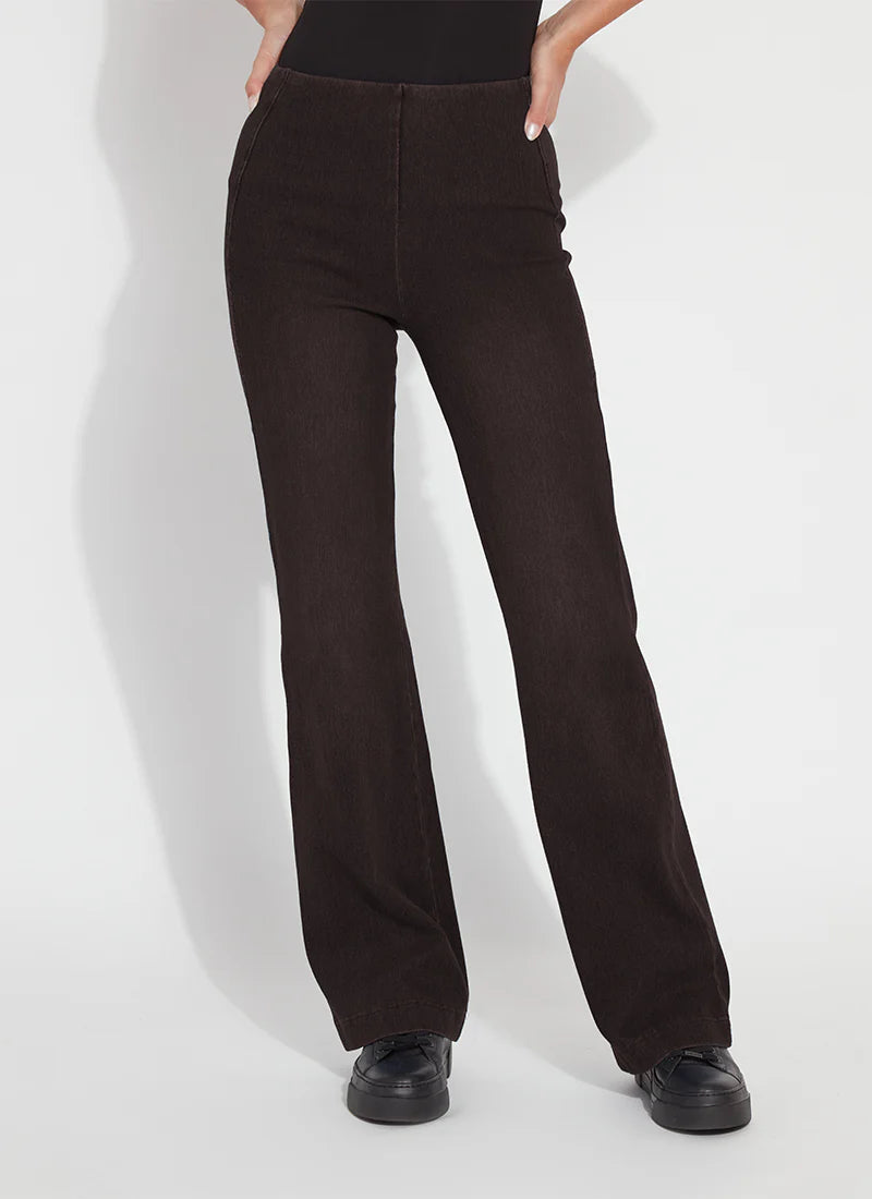 A person wearing dark brown wide-leg pants with a black top and black shoes, standing against a light gray studio background.