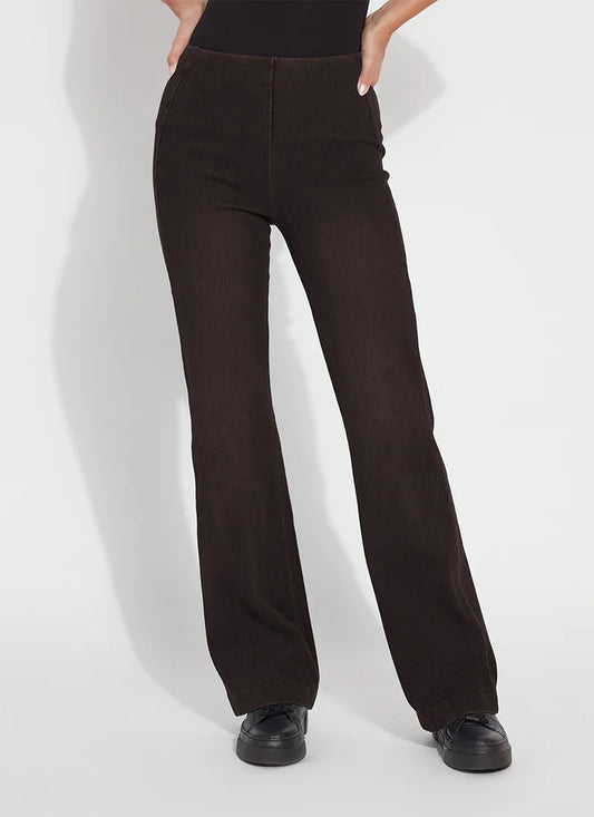 A person wearing dark brown wide-leg pants with a black top and black shoes, standing against a light gray studio background.